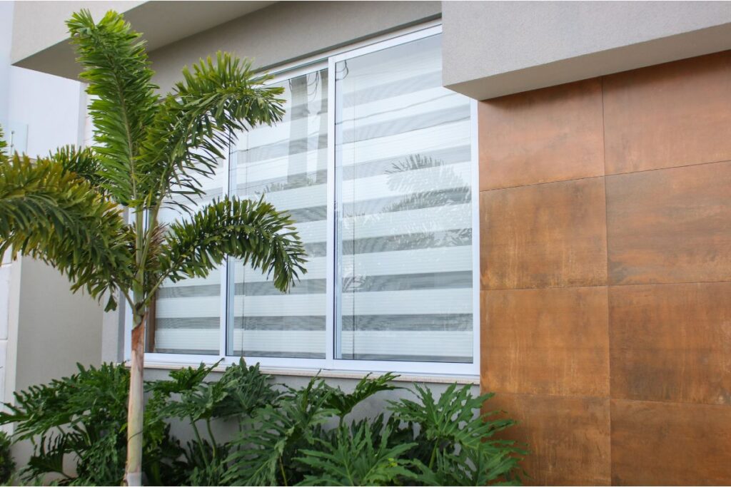 Ventana con persiana de doble visión bajada en la fachada de una vivienda moderna.