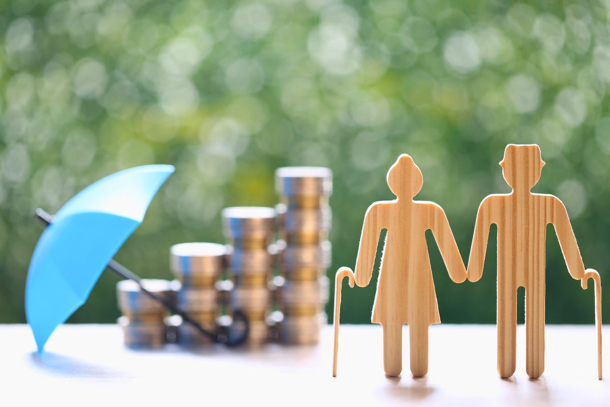 Figuras de madera representando a jubilados con bastón, un paraguas y ahorros.