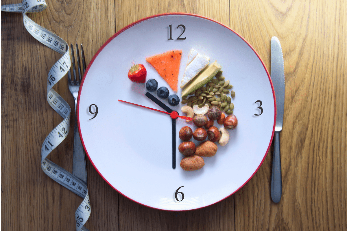 Un reloj en forma de plato con alimentos en las horas en las que se permite comer y una cinta métrica al lado.