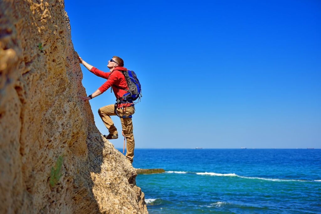 siempre hacia arriba - Prueba Esto Hoy Una persona está escalando una montaña bajo el sol, simbolizando la superación de obstáculos y la esperanza en el camino hacia sus sueños. Esta imagen refleja la valentía y la determinación necesarias para enfrentar los desafíos de la vida.