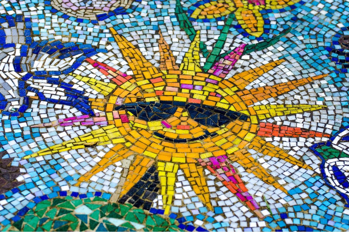 Mosaico de teselas de colores con un sol amarillo y naranja en el centro.