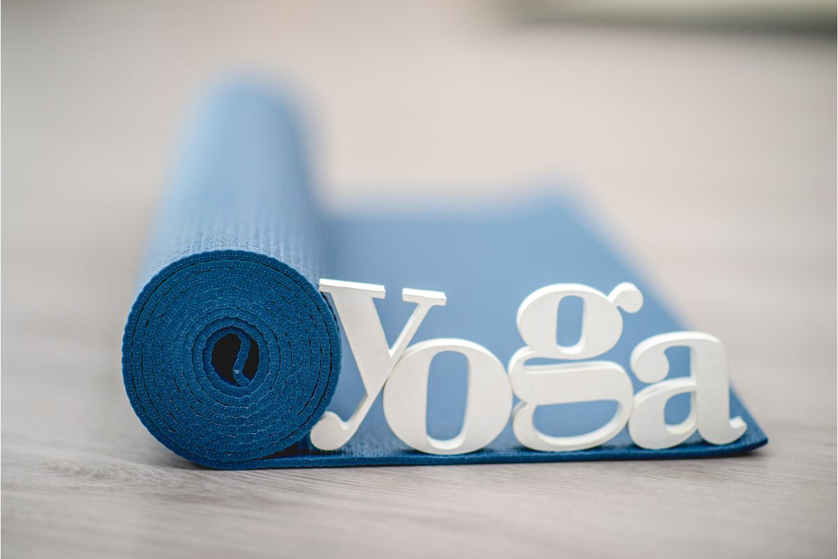 La palabra yoga sobre una esterilla para hacer yoga enrollaa.