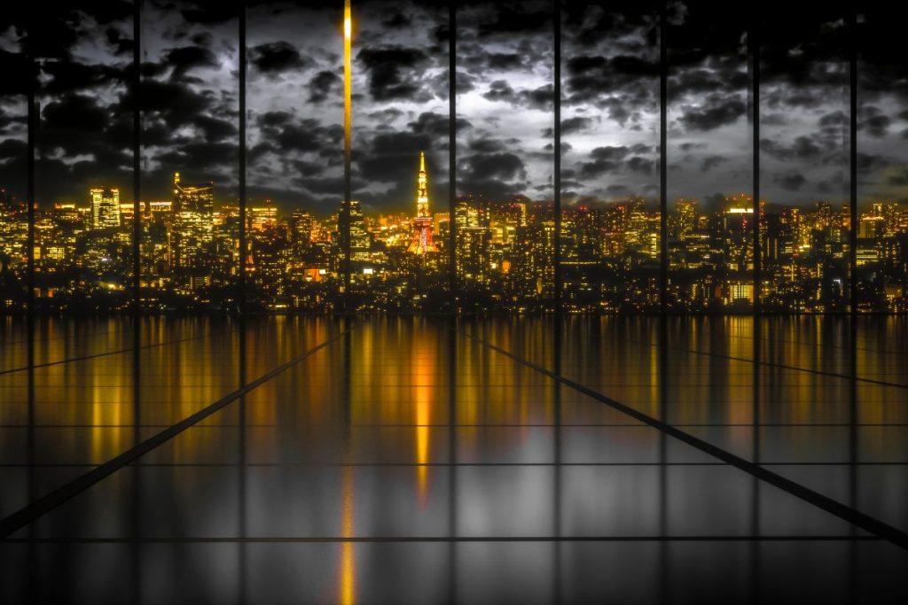 Las luces de la ciudad reflejadas sobre el agua fotografiadas a través del cristal de una ventana.