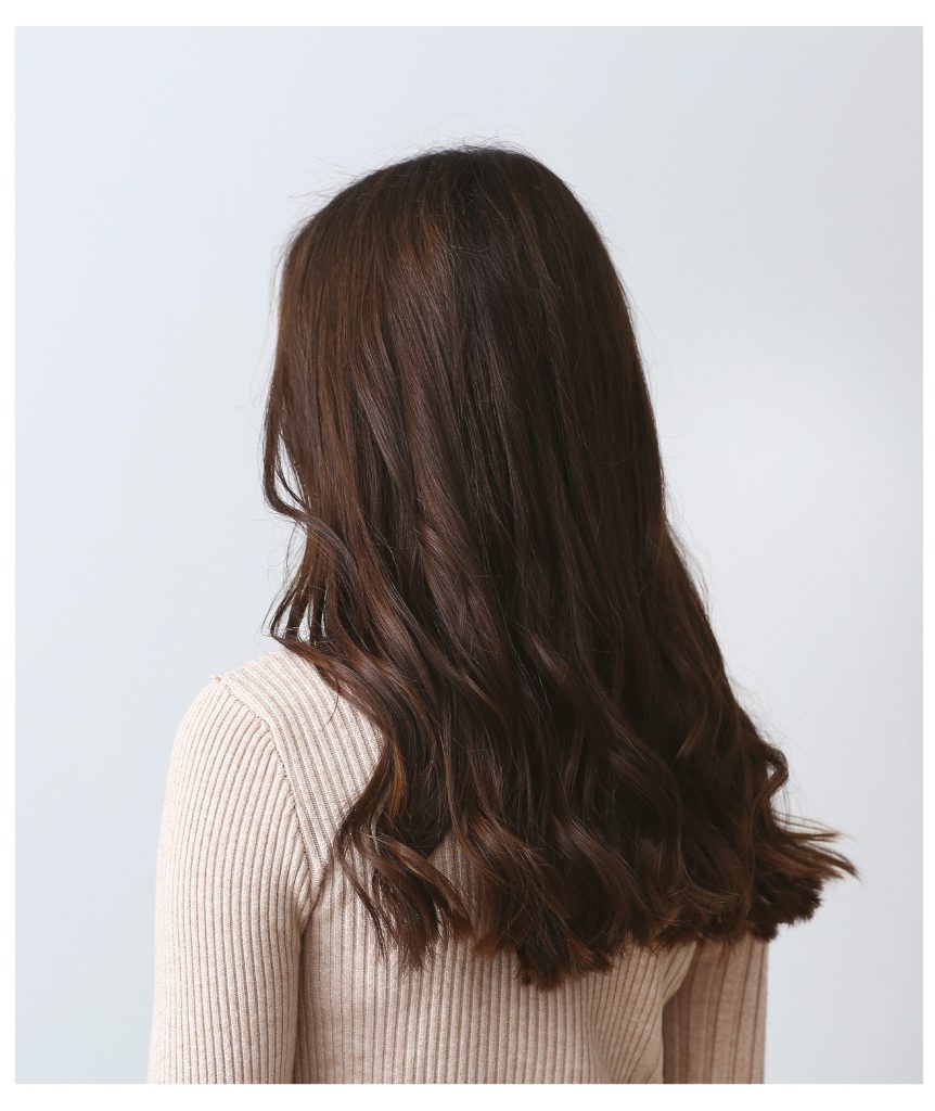 Una mujer con el pelo limpio y peniado, lista para hacer un moño.