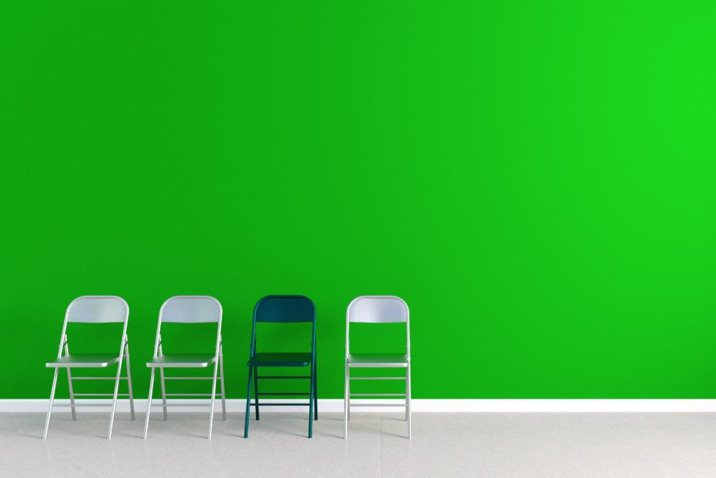 Tres sillas grises y una negra delante de una pared verde, representando el concepto de propuesta única de venta.