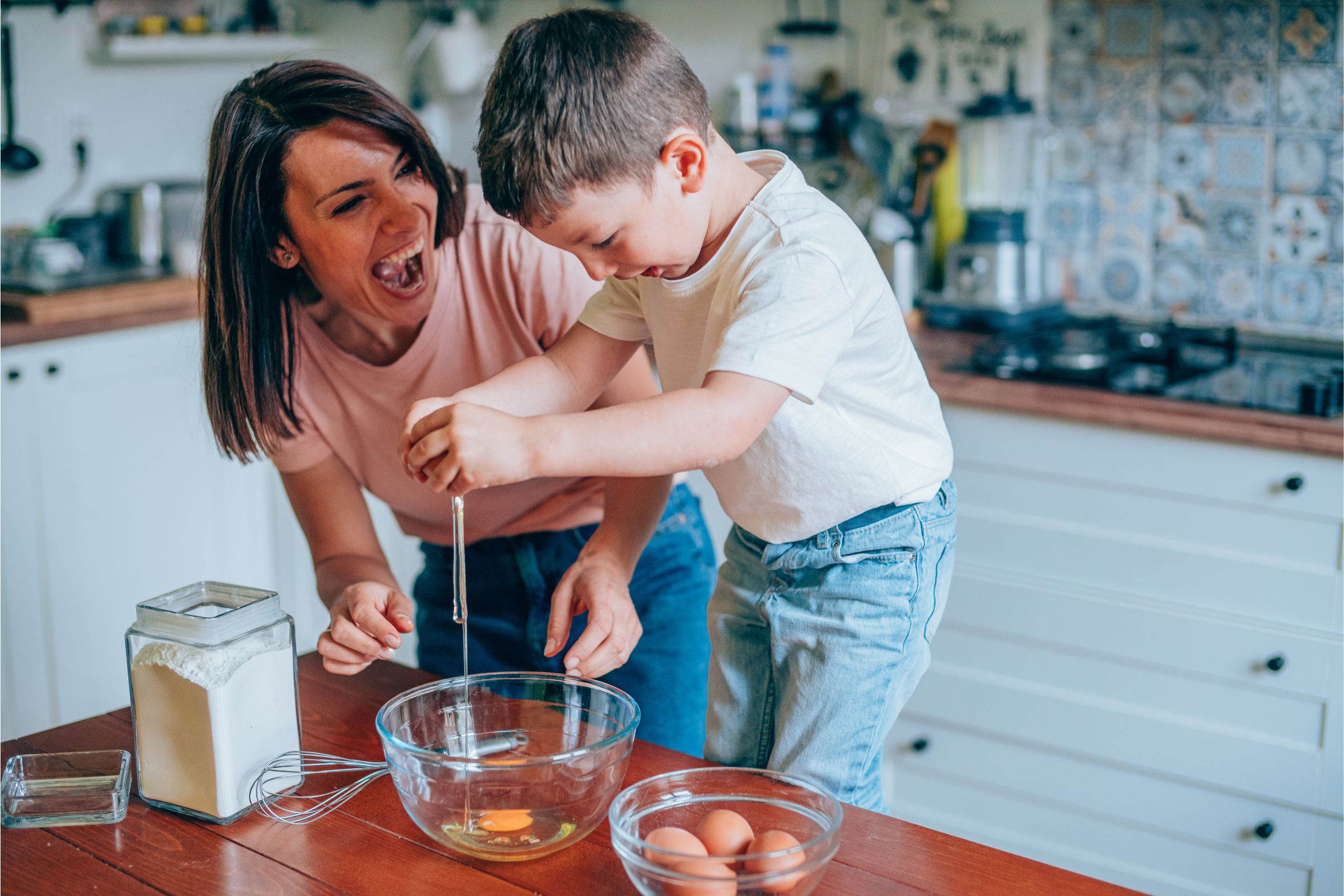 Madree hijo en la cocina< el hijo casca un huevo y su madre lo celebra.