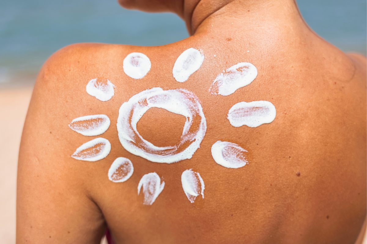 Un sol dibujado con crema de protección solar en la espalda de una persona.