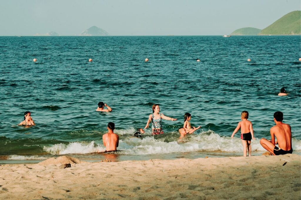 Gente disfrutando en la playa y nadando en el mar.