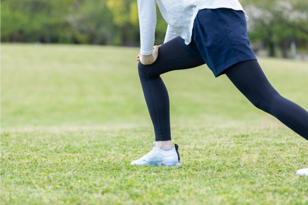 Una persona haciendo estiramientos sobre la hierba.