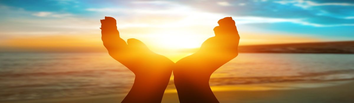Manos enmarcando el sol, concepto de solsticio de verano.