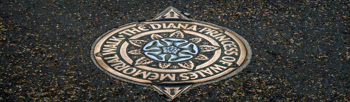 Placa de bronce de la Ruta Conmemorativa de Diana, Princesa de Gales, incrustada en el pavimento de Londres, con una rosa estilizada en el centro.